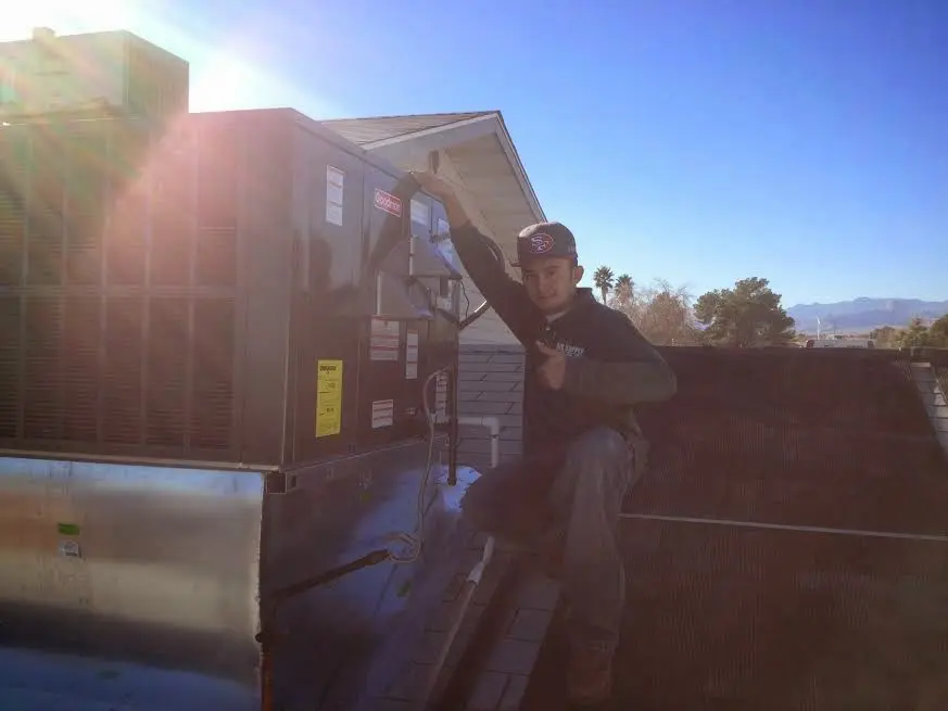 HVAC technician performing Air Duct Cleaning on a rooftop unit in DeWitt